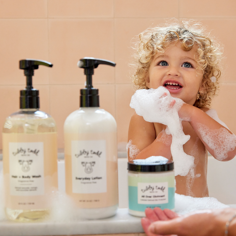 Toddler in bath tub with Fragrance free Hair + Body Wash and Everyday Lotion and All Over Ointment