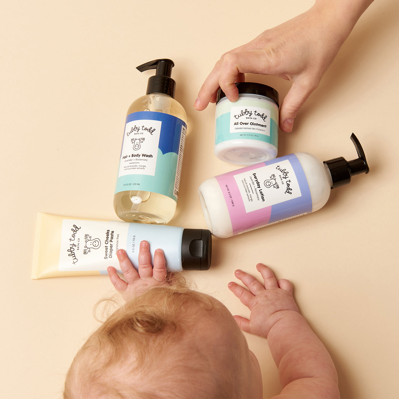 Baby laying next to Baby Bundle products on background.