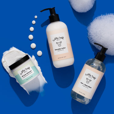 Three bottles of 'Nubby Tddy' baby products on a blue background