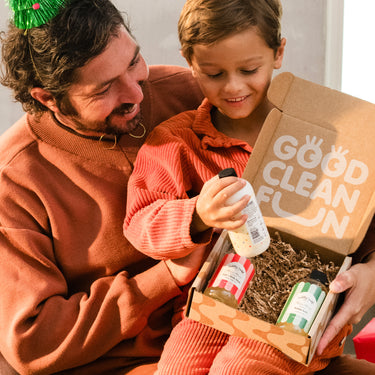 Man and child opening a 'Good Clean Fun' box with cleaning products.