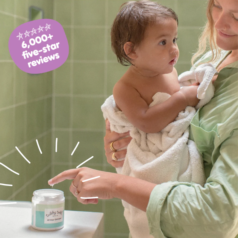 Mama holding her baby while dipping her finger in All Over Ointment in green tiles bathroom and in upper left corner there is a purple circle that says 6000 five stars reviews