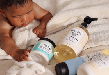 Baby interacting with baby care products on a soft surface