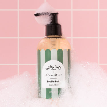 Bottle of bubble bath with a striped design on a pink tiled background