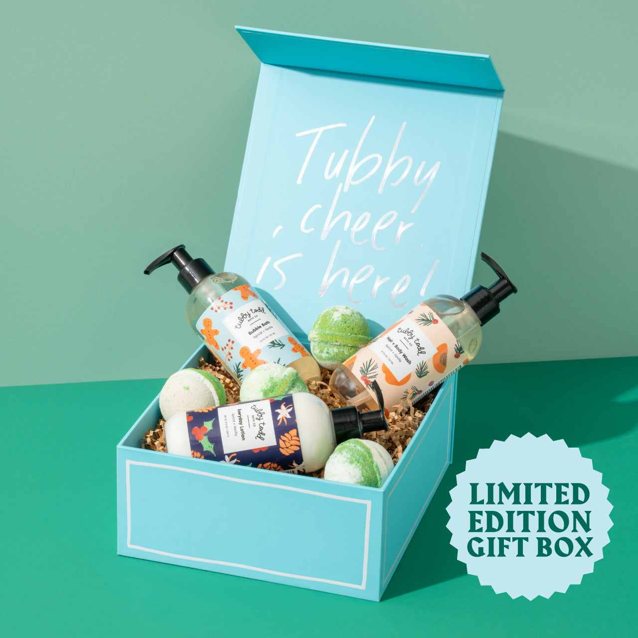 Blue gift box with Tubby Evergreen bottles and the bath bombs on the green background.