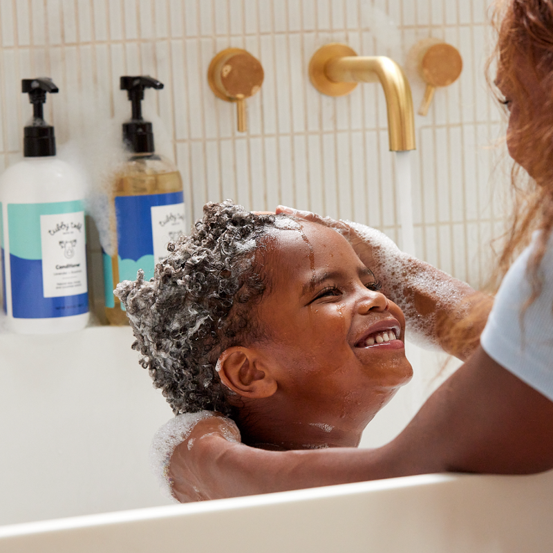 Mother washing child's hair in tub with Hair + Body Wash