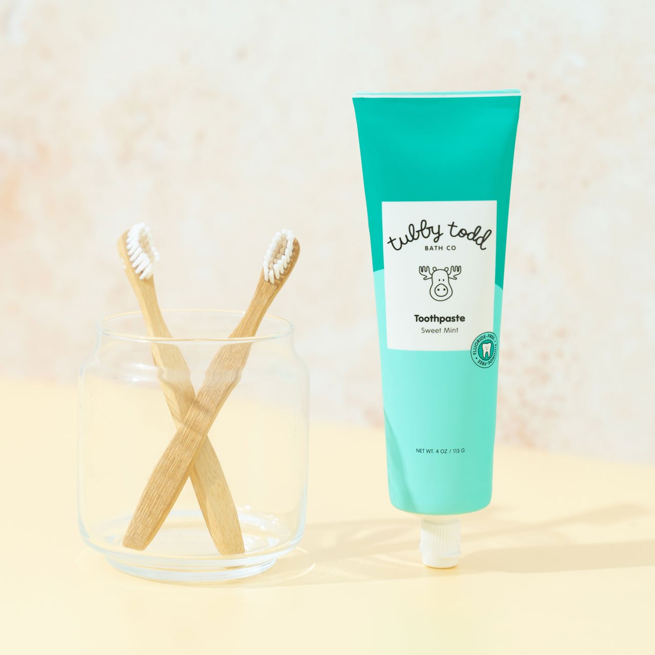 Sweet Mint Toothpaste next to jar with kids' bamboo toothbrushes