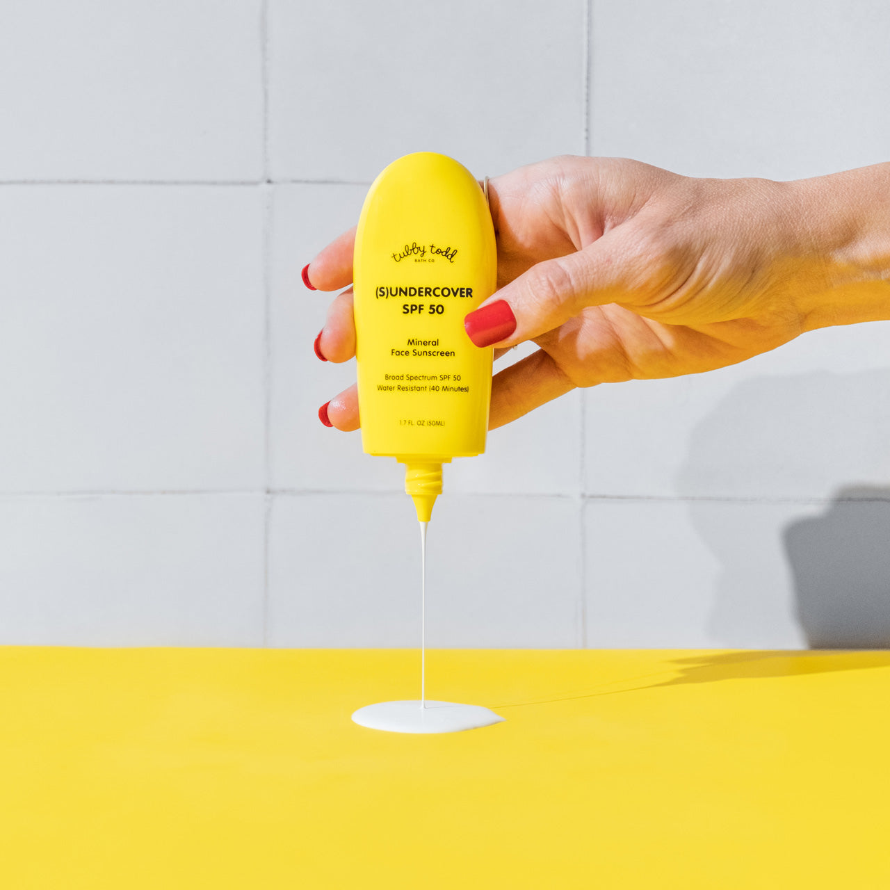 Mama squeezing (S)undercover product onto yellow table