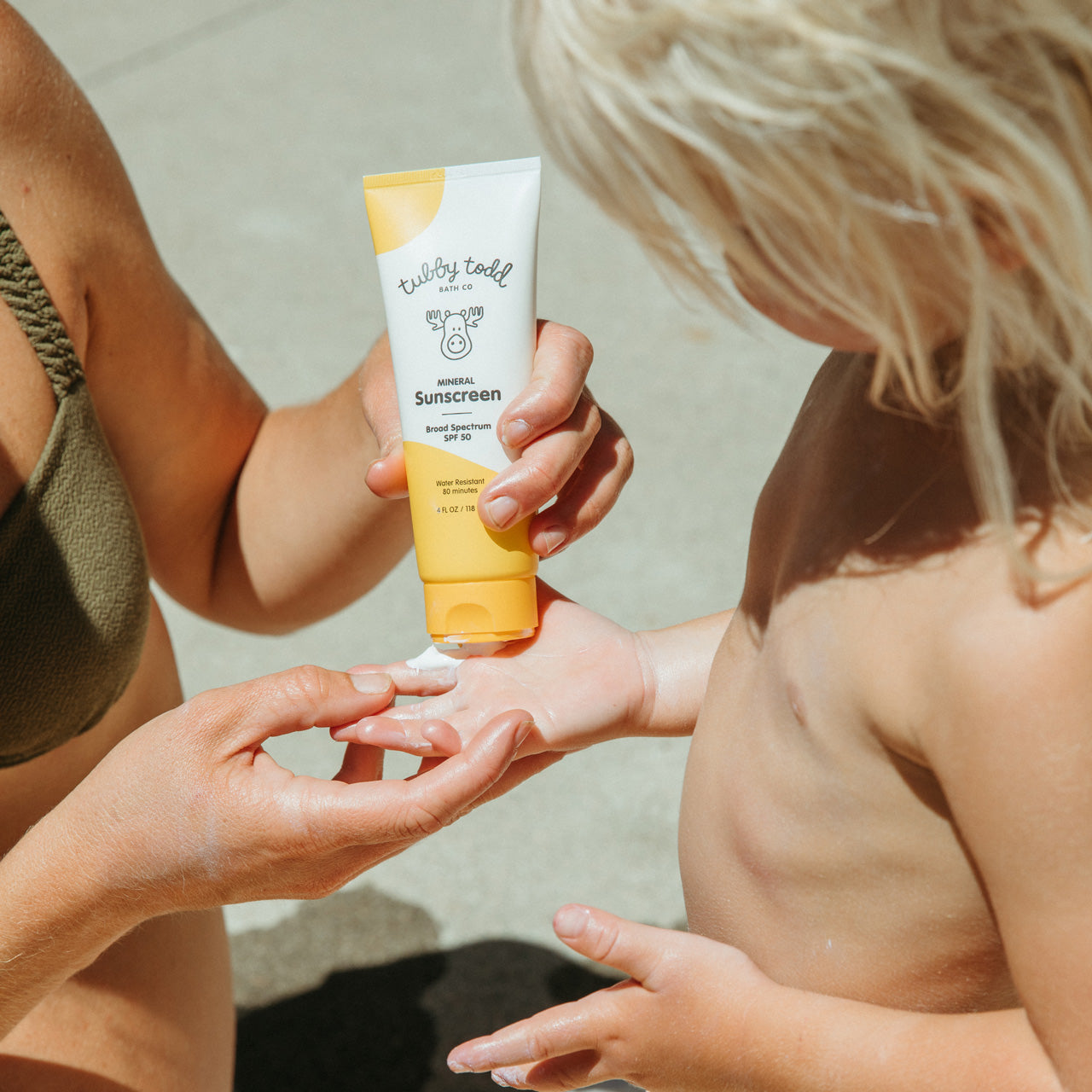 Mama applying Mineral Sunscreen to child's hand