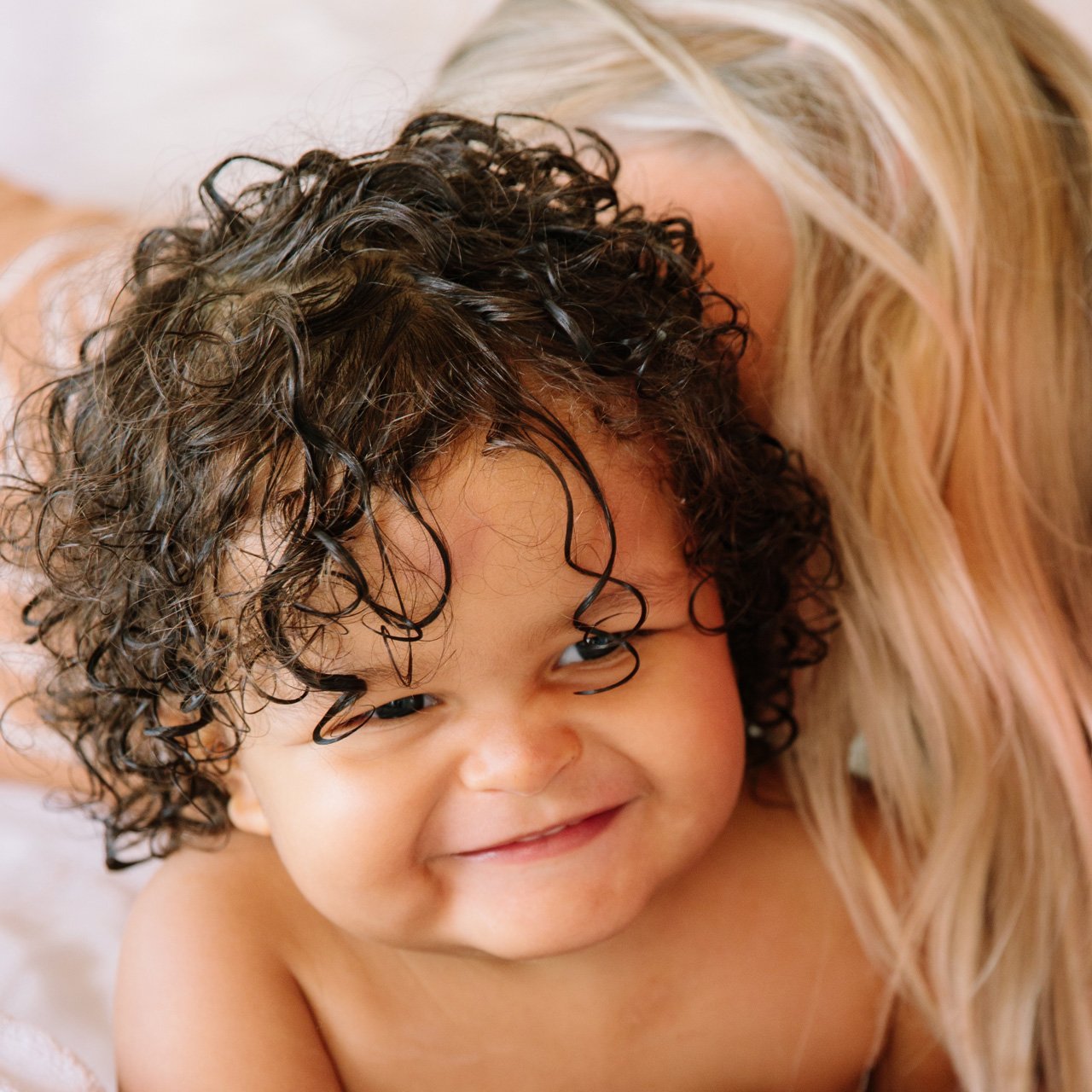 Mom cuddling toddler with curly hair
